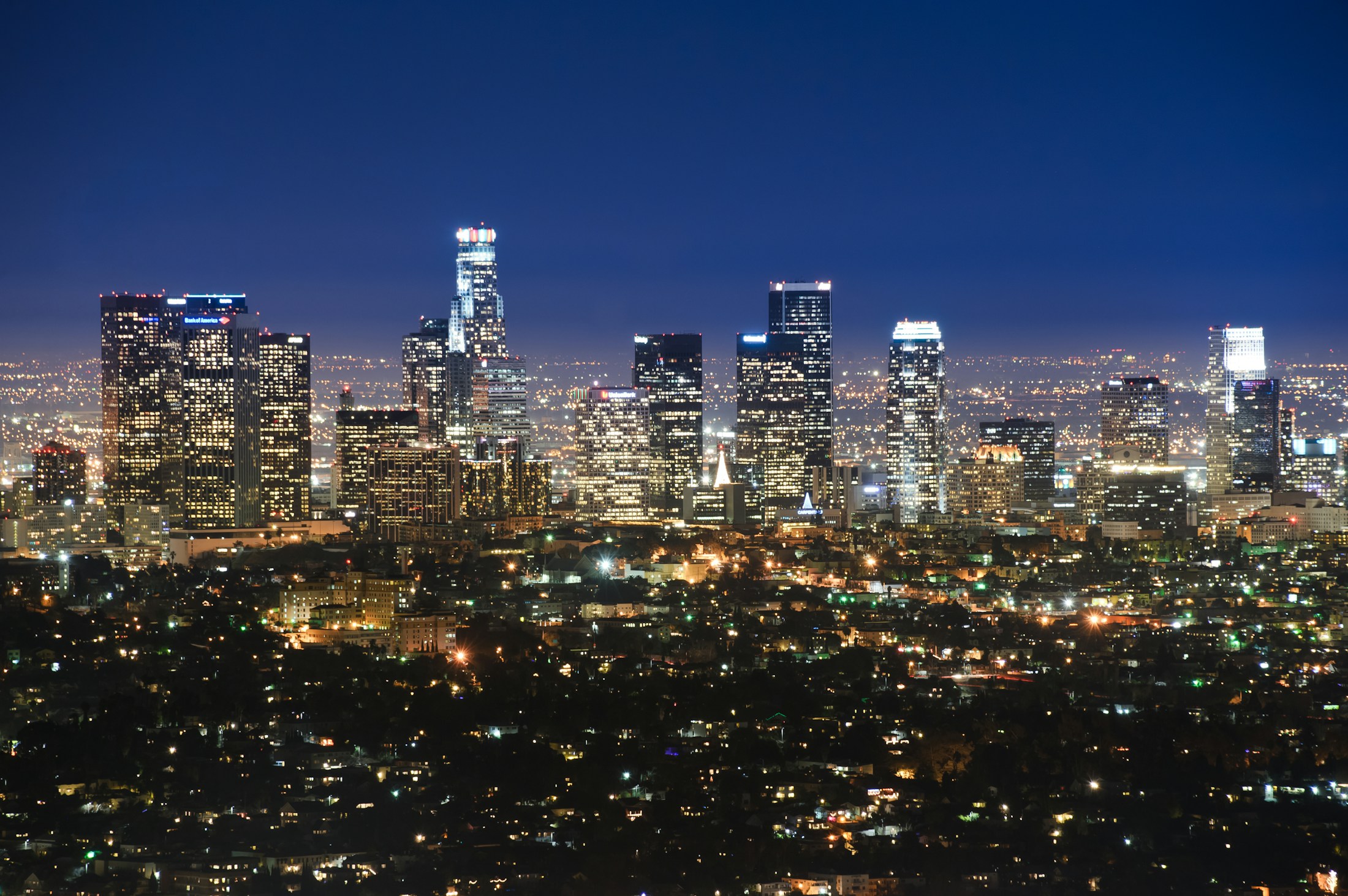 Downtown Los Angeles skyline illuminated beneath a deep blue evening sky